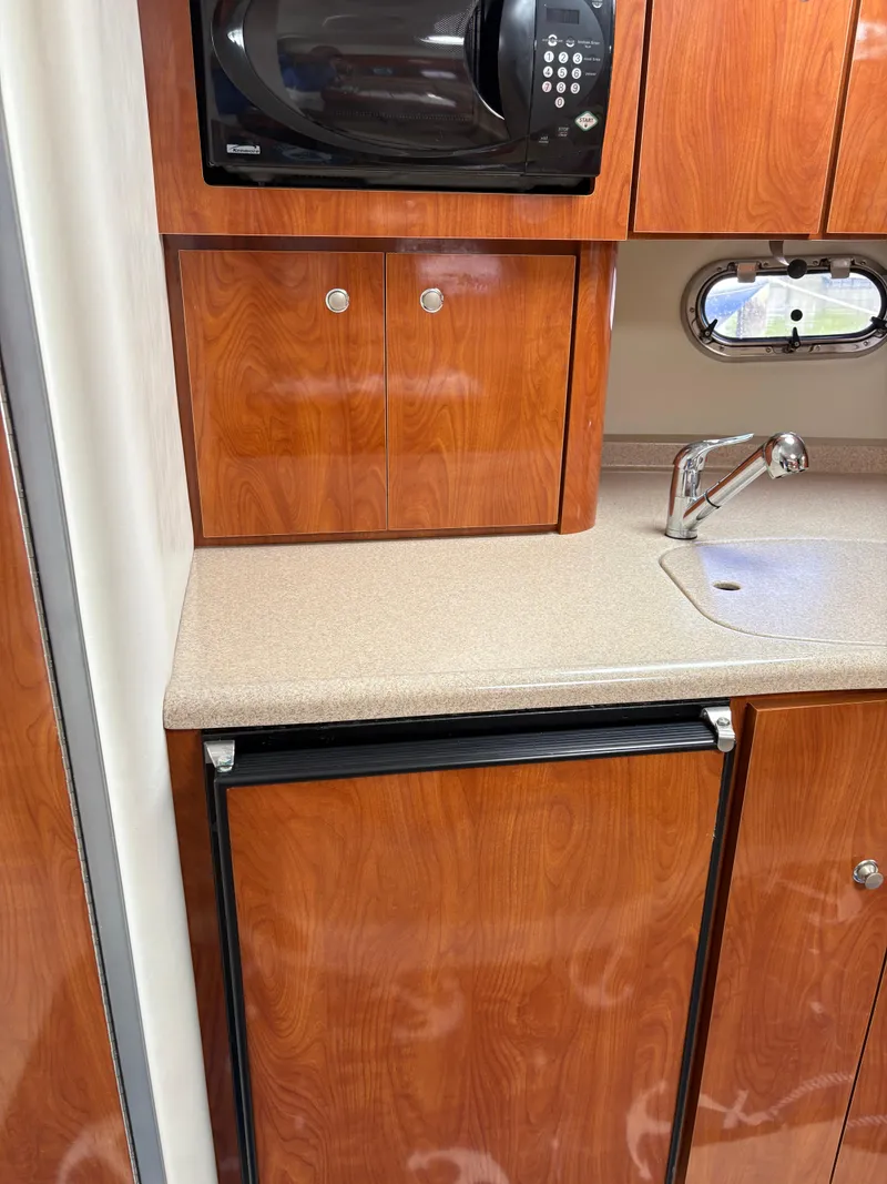 Slide: The Image of 2005 Four Winns 328 Vista Cruiser kitchen with wood cabinets, microwave, and sink. - 8