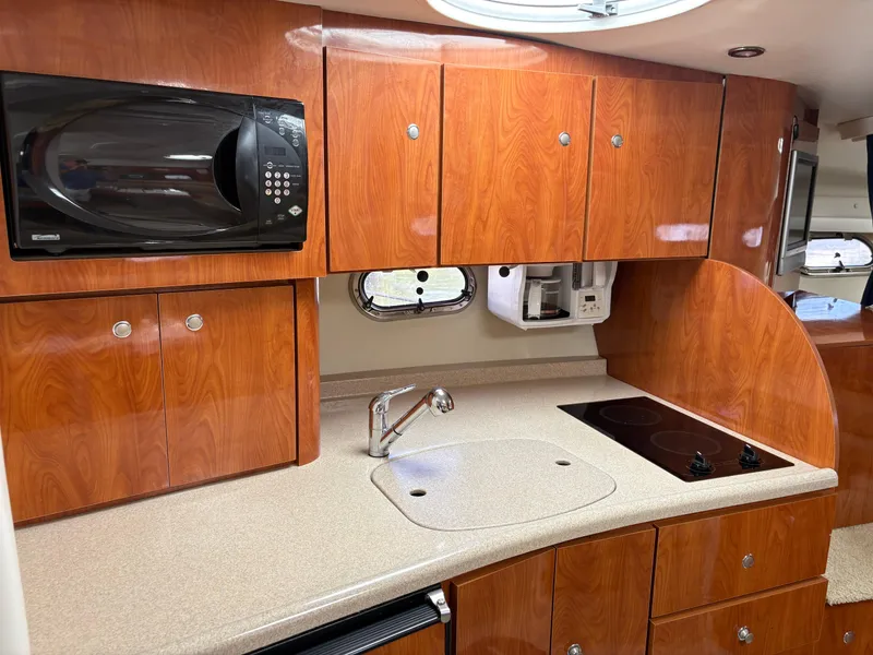 Slide: The Image of 2005 Four Winns 328 Vista Cruiser kitchen with wood cabinets, microwave, and stovetop. - 9