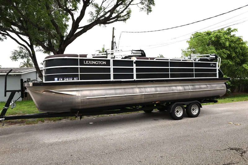 Slide: The Image of 2021 Lexington 525 cc pontoon boat on trailer, parked on a residential street. - 1