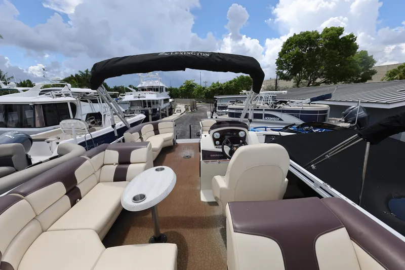 Slide: The Image of 2021 Lexington 525 cc pontoon boat with spacious seating and helm, docked among other boats. - 21