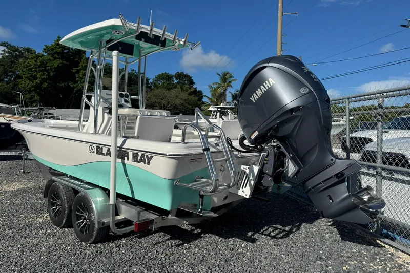 Slide: The Image of 2026 Blazer PureBay 2400 boat with Yamaha engine on trailer, parked outdoors. - 1