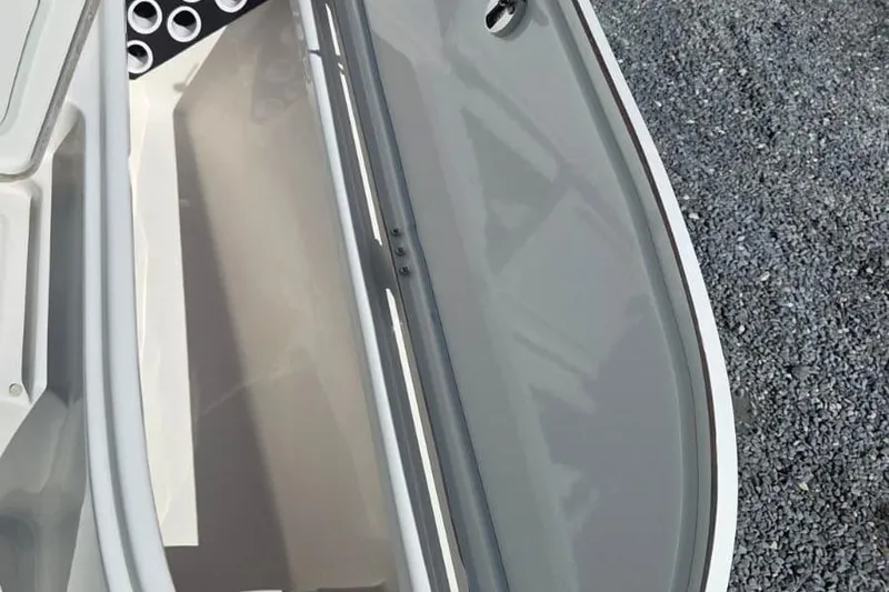 Slide: The Image of 2026 Blazer PureBay 2400 boat deck with storage compartment, gravel background. - 15