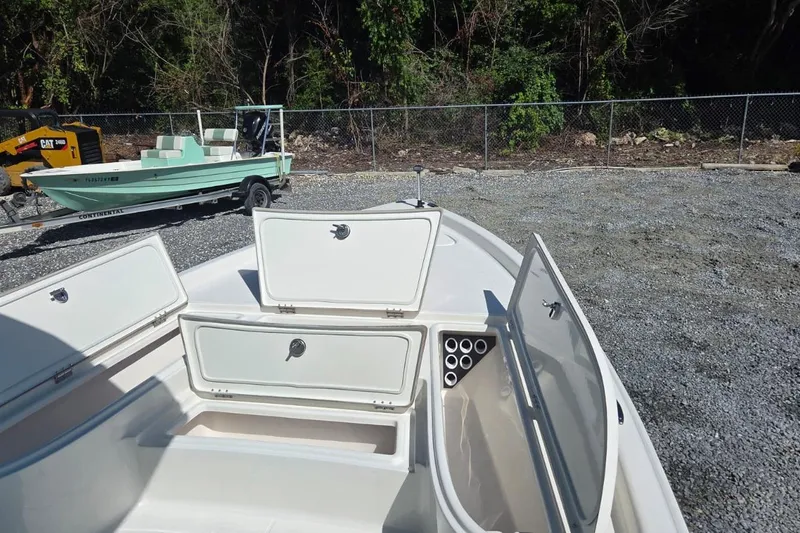 Slide: The Image of 2026 Blazer PureBay 2400 boat with open storage compartments, parked on gravel. - 16