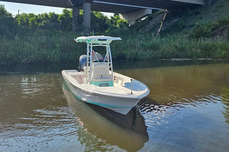 Slide: The Image of 2026 Blazer PureBay 2400 boat on calm river under bridge, surrounded by greenery. - 18