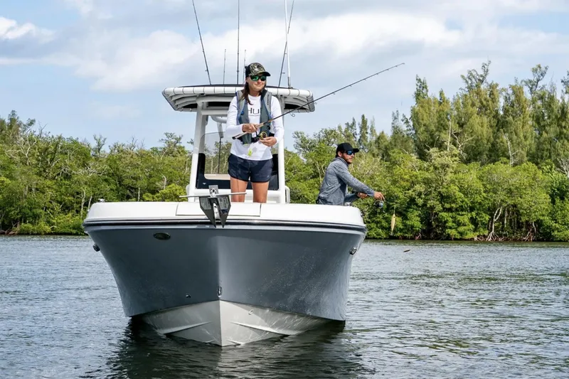 Slide: The Image of 2025 Bayliner Trophy T24CC boat interior with seating and console, parked outdoors. - 2