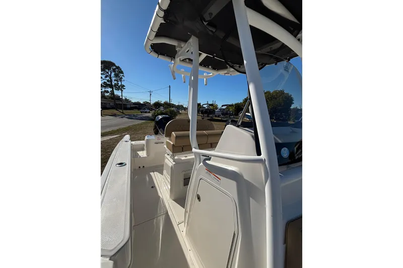 Slide: The Image of 2025 Bayliner Trophy T24CC boat interior with seating and console, parked outdoors. - 7