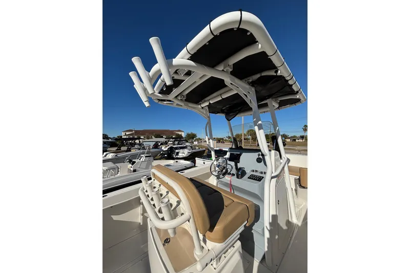 Slide: The Image of 2025 Bayliner Trophy T24CC boat interior with seating and console, under clear blue sky. - 8