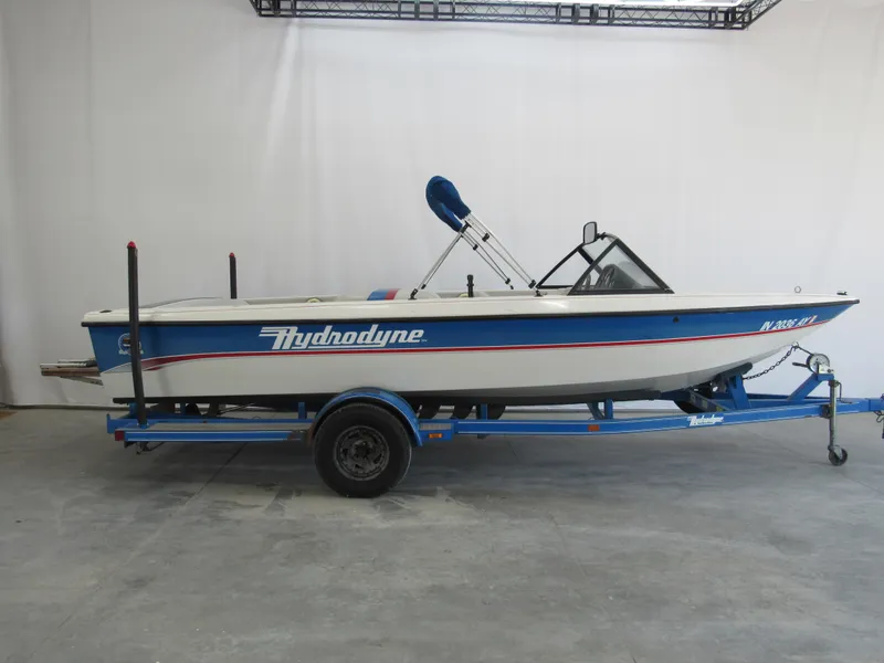 The Image of 1993 Hydrodyne Comp boat on trailer, blue and white design, indoor setting. - 0