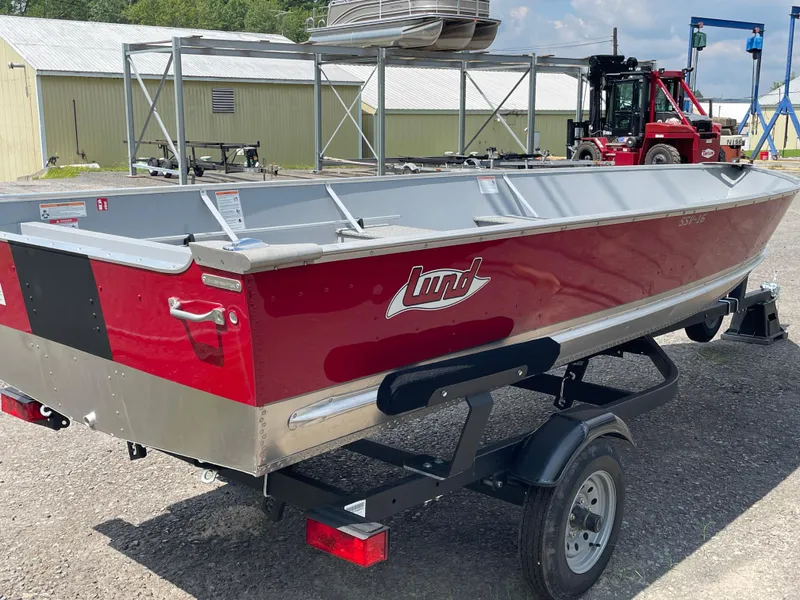 Slide: The Image of 2026 Lund SSV-16 boat in red on a trailer, parked outdoors. - 3