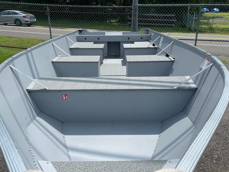 Slide: The Image of 2026 Lund SSV-16 boat interior with seating, parked near a chain-link fence. - 5
