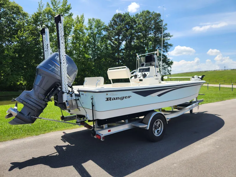 Slide: The Image of 2011 Ranger 220 Bahia boat on trailer, parked on a sunny day with trees in background. - 2