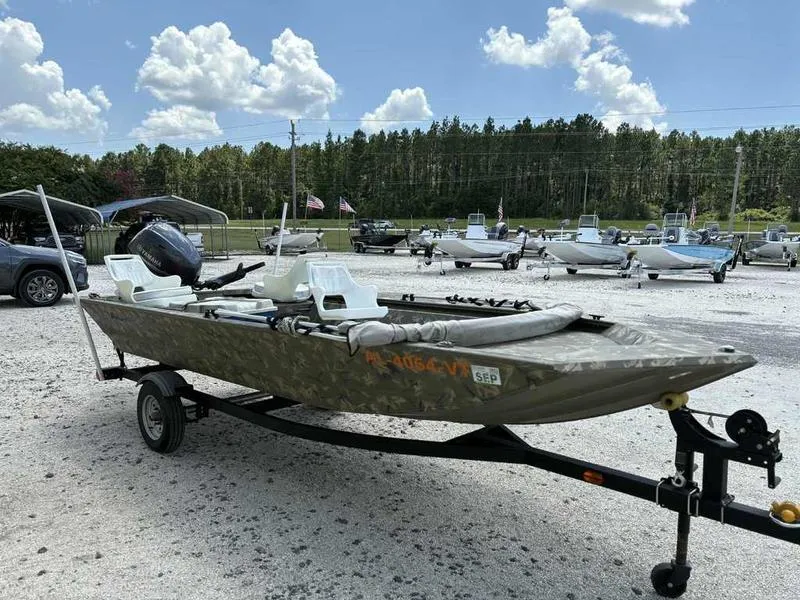 Slide: The Image of 2023 Tracker Grizzly 1648 Jon boat on trailer, parked outdoors under a blue sky. - 2