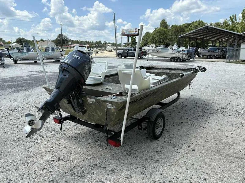 Slide: The Image of 2023 Tracker Grizzly 1648 Jon boat with motor on trailer in outdoor setting. - 5