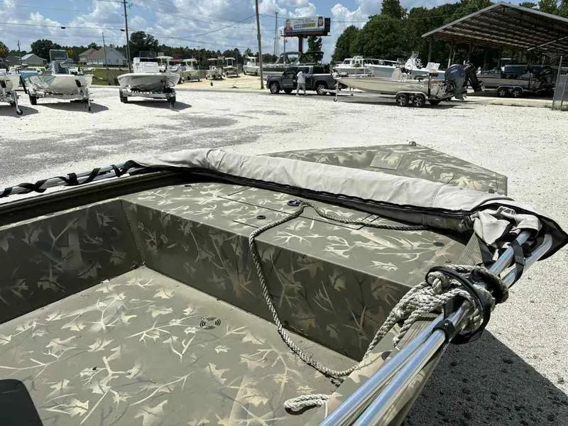 Slide: The Image of 2023 Tracker Grizzly 1648 Jon boat with camouflage design in a boatyard. - 8