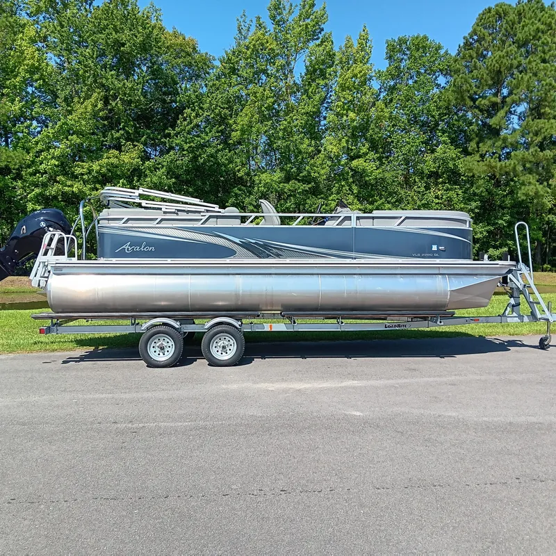 The Image of 2022 Avalon VLS Quad Lounge pontoon boat on trailer, parked outdoors. - 0