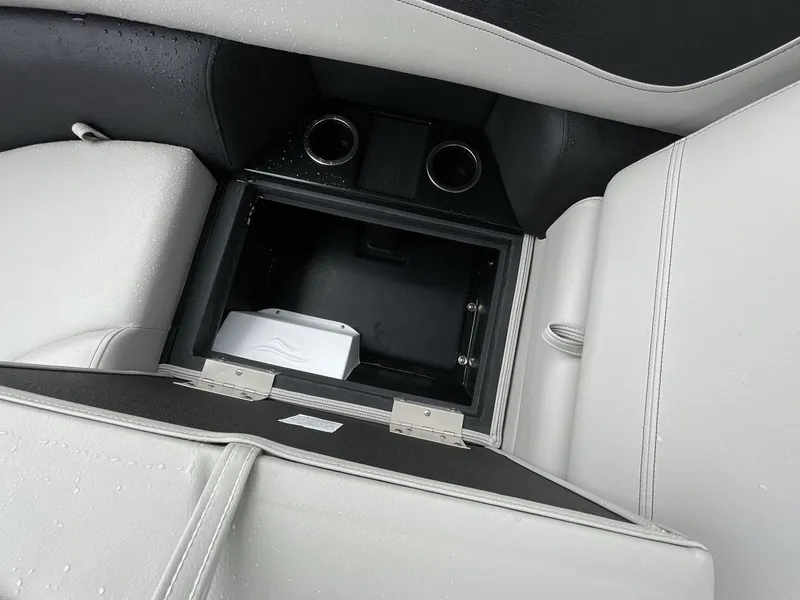Slide: The Image of Open storage compartment in 2025 South Bay 222RSLE boat with cup holders and white seating. - 18