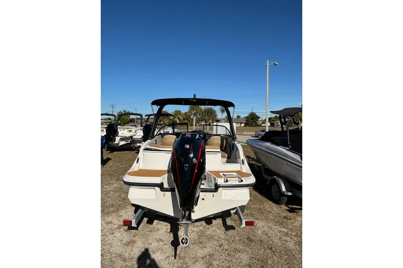 Slide: The Image of 2025 Bayliner V20 boat, rear view, parked on grass under clear blue sky. - 5