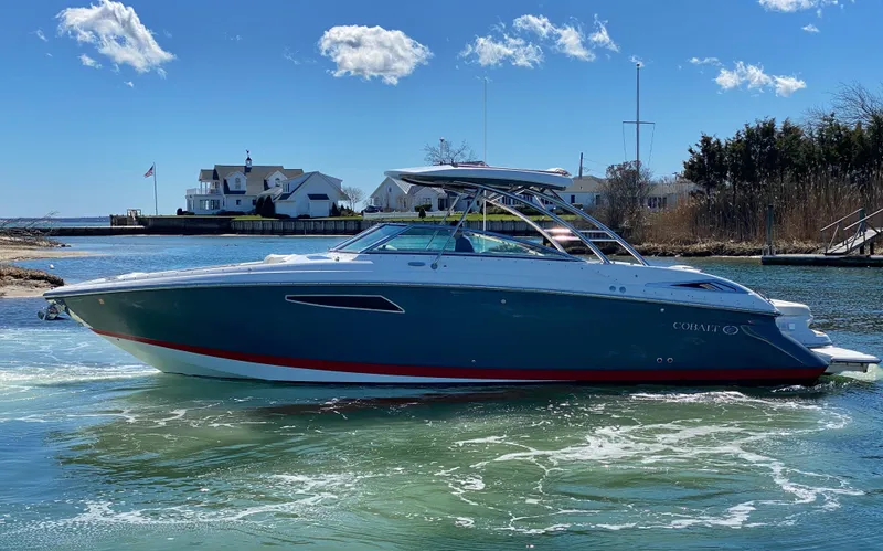 The Image of 2018 Cobalt R35 boat cruising on a sunny day near waterfront homes. - 0
