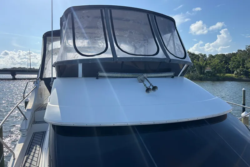 Slide: The Image of 2001 Silverton 410 Sport Bridge yacht docked on a sunny day, featuring sleek design and clear canopy. - 61