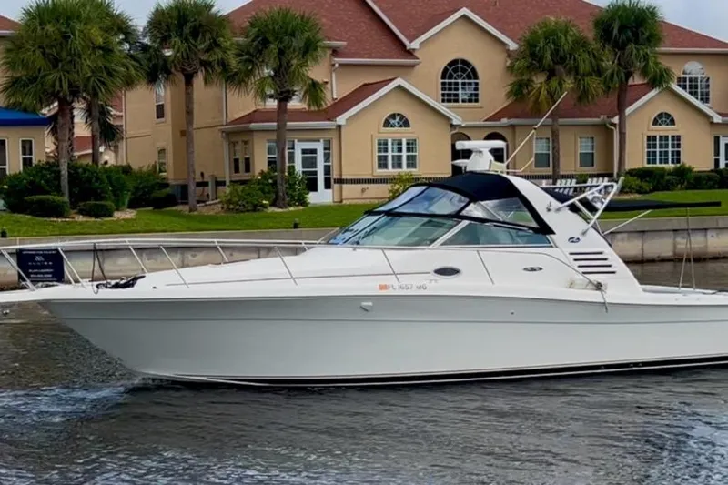 The Image of 2001 Sea Ray 340 Amberjack boat cruising near waterfront homes with palm trees. - 1