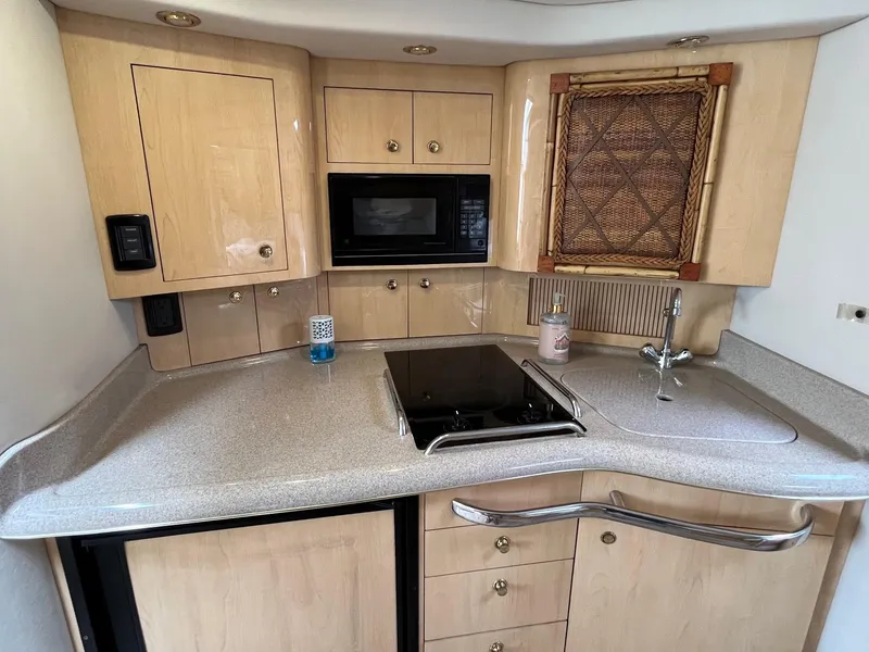 Slide: The Image of 2001 Sea Ray 340 Amberjack boat kitchen with stove, sink, and microwave. - 12