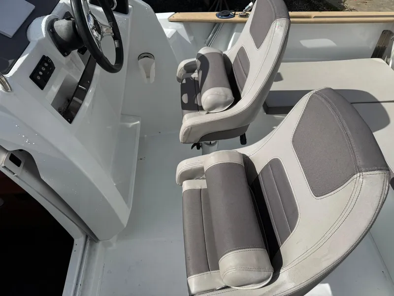 Slide: The Image of 2015 Jeanneau Cap Camarat 6.5 WA boat interior with two cushioned seats and steering wheel. - 2