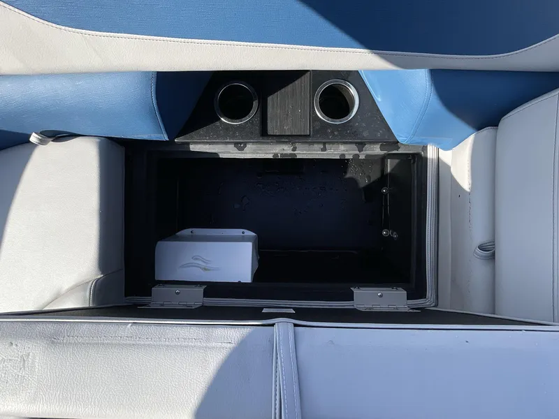 Slide: The Image of 2025 South Bay 224RSLE boat storage compartment with cup holders and blue-white seating. - 12