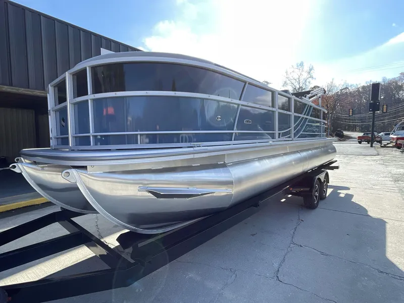 Slide: The Image of 2025 South Bay 224RSLE pontoon boat on trailer, parked outdoors. - 2