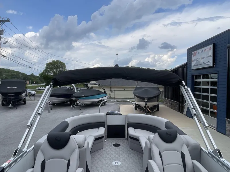 Slide: The Image of 2025 South Bay 224RSLE pontoon boat with sleek seating and canopy, parked outdoors. - 12