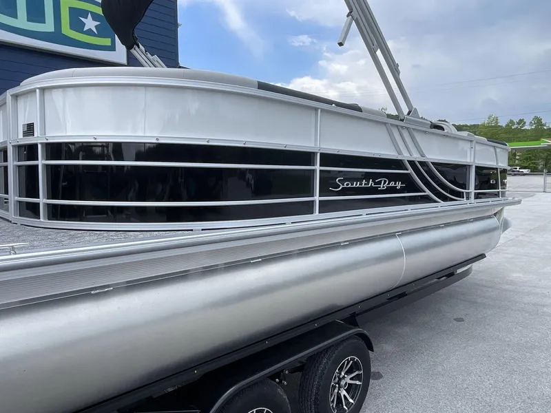 Slide: The Image of 2025 South Bay 224RSLE pontoon boat on trailer, sleek design under blue sky. - 7
