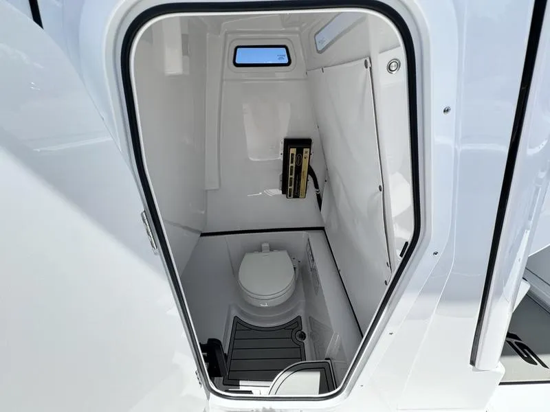Slide: The Image of 2025 Sportsman Heritage 261 boat interior with compact marine toilet and window. - 11