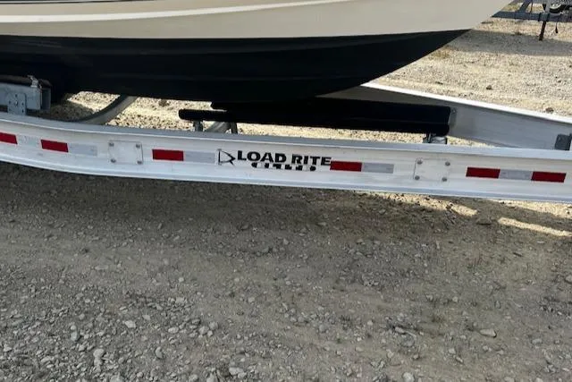 Slide: The Image of 1999 Contender 27 Open Center Console on Load Rite trailer, parked on gravel. - 15