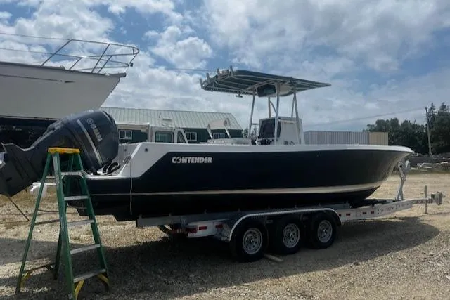 Slide: The Image of 1999 Contender 27 Open Center Console boat on trailer, parked outdoors under cloudy sky. - 18