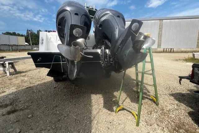 Slide: The Image of 1999 Contender 27 Open Center Console with dual outboard motors on a gravel lot. - 22