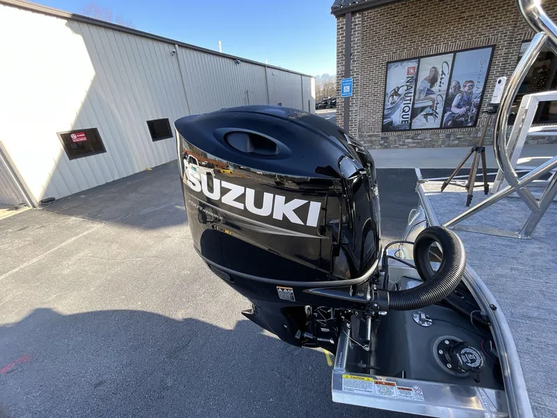 Slide: The Image of Suzuki outboard motor on 2025 South Bay 224ULLE boat, parked near industrial buildings. - 10