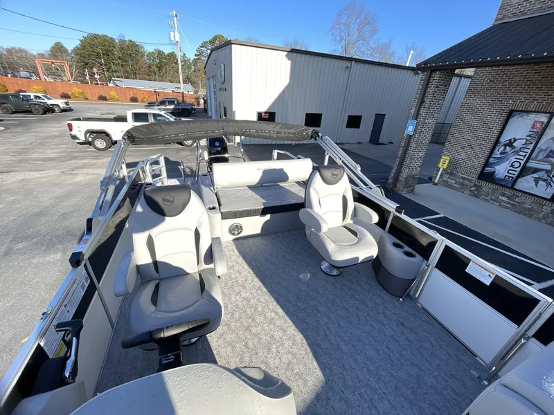 Slide: The Image of 2025 South Bay 224ULLE pontoon boat interior with seating and helm, parked outdoors. - 12