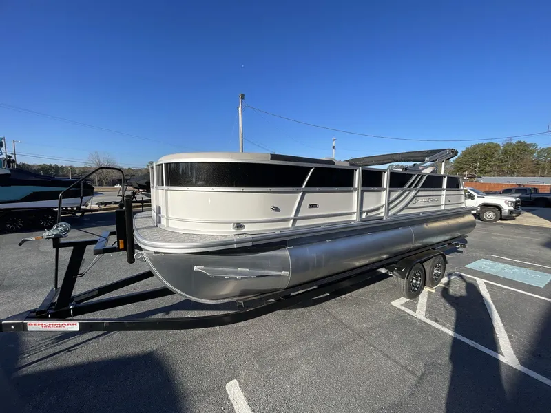 Slide: The Image of 2025 South Bay 224ULLE pontoon boat on trailer, parked outdoors under clear blue sky. - 2