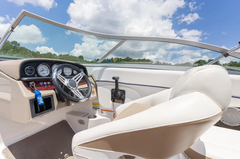 Slide: The Image of 2008 Four Winns F224 boat interior with steering wheel, gauges, and white seating under blue sky. - 23