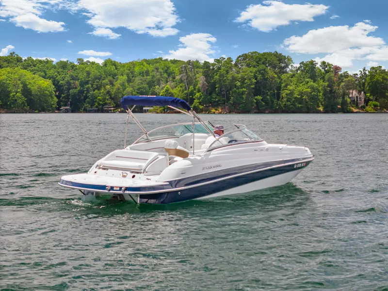 Slide: The Image of 2008 Four Winns F224 boat cruising on a scenic lake with lush green trees. - 3