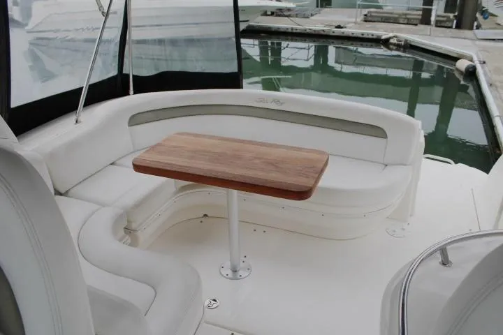 Slide: The Image of 2007 Sea Ray 340 Sundancer interior with white seating and wooden table, docked at marina. - 12