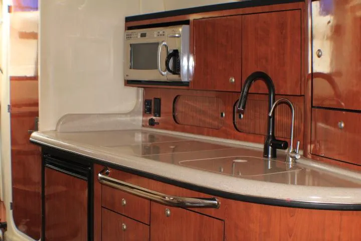 Slide: The Image of 2007 Sea Ray 340 Sundancer kitchen with wood cabinets, microwave, and sleek countertop. - 38
