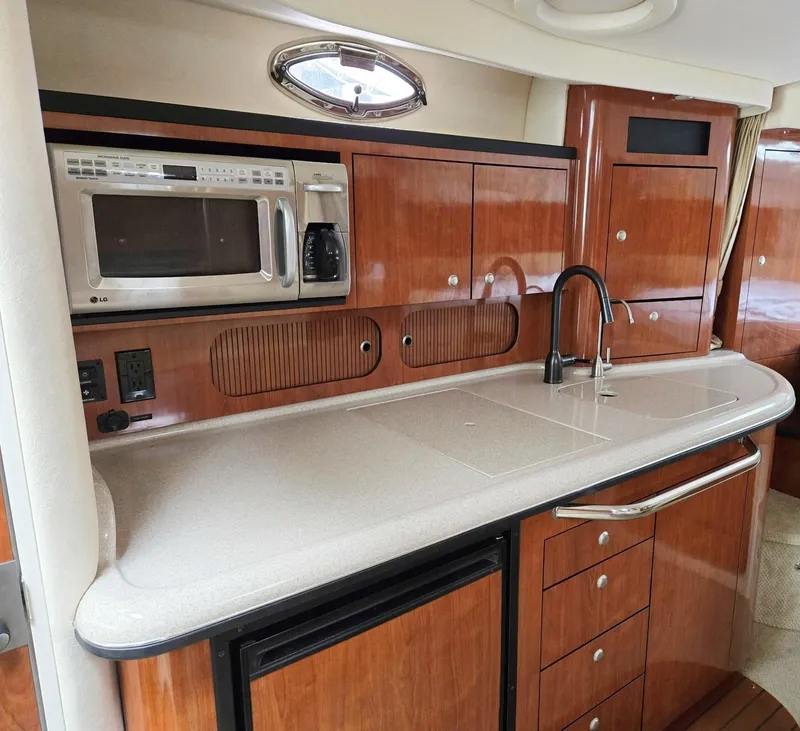 Slide: The Image of 2007 Sea Ray 340 Sundancer kitchen with microwave, sink, and wooden cabinetry. - 40
