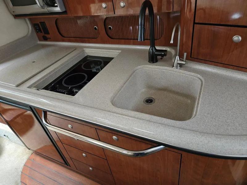 Slide: The Image of 2007 Sea Ray 340 Sundancer kitchen with sink, stovetop, and wooden cabinetry. - 42