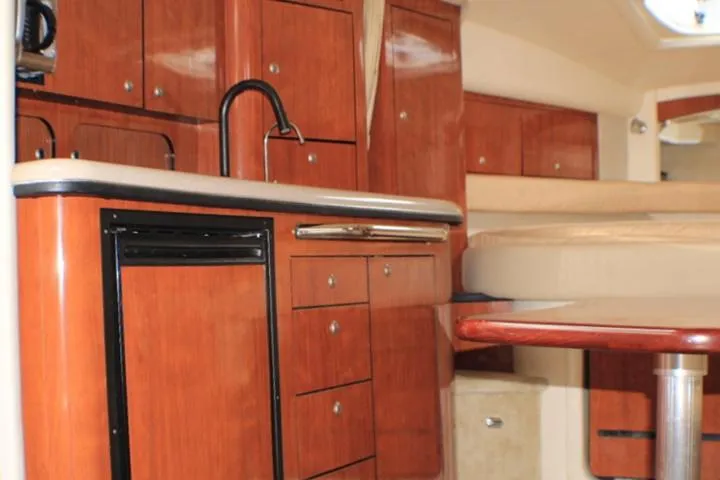 Slide: The Image of 2007 Sea Ray 340 Sundancer interior with wood cabinetry and compact kitchen area. - 45