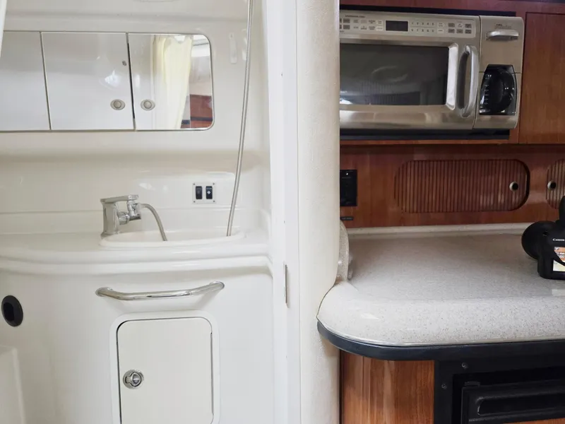 Slide: The Image of 2007 Sea Ray 340 Sundancer interior with kitchenette, featuring sink, microwave, and storage cabinets. - 52