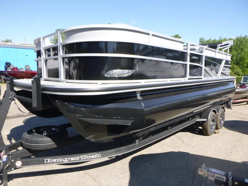 Slide: The Image of 2024 Ranger Reata 223C pontoon boat on trailer, black and silver design. - 4