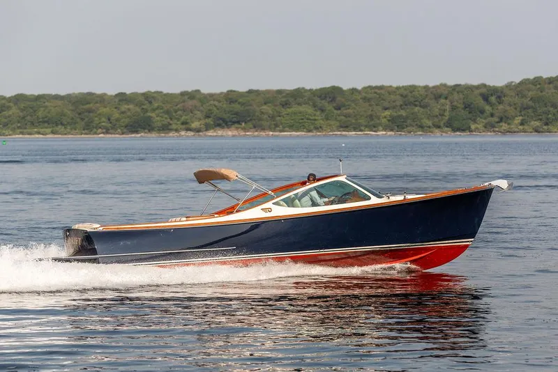 Slide: The Image of 2003 Hinckley Talaria 29R cruising on calm waters with lush green shoreline. - 1