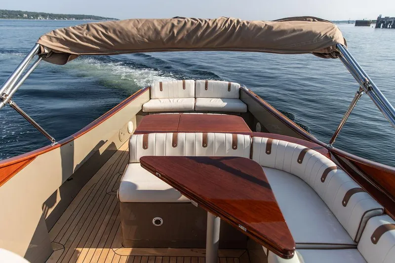 Slide: The Image of 2003 Hinckley Talaria 29R boat interior with elegant seating and wooden table on calm water. - 14