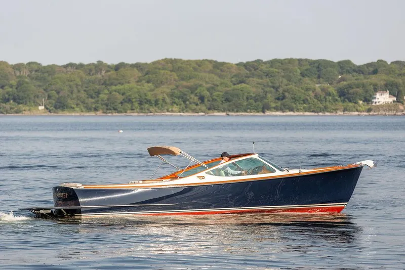 Slide: The Image of 2003 Hinckley Talaria 29R cruising on calm waters with lush green shoreline. - 2