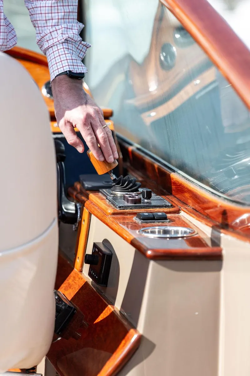 Slide: The Image of Man operating controls on a 2003 Hinckley Talaria 29R boat with wooden dashboard. - 32